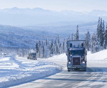 Semi truck driving over a snowy pass